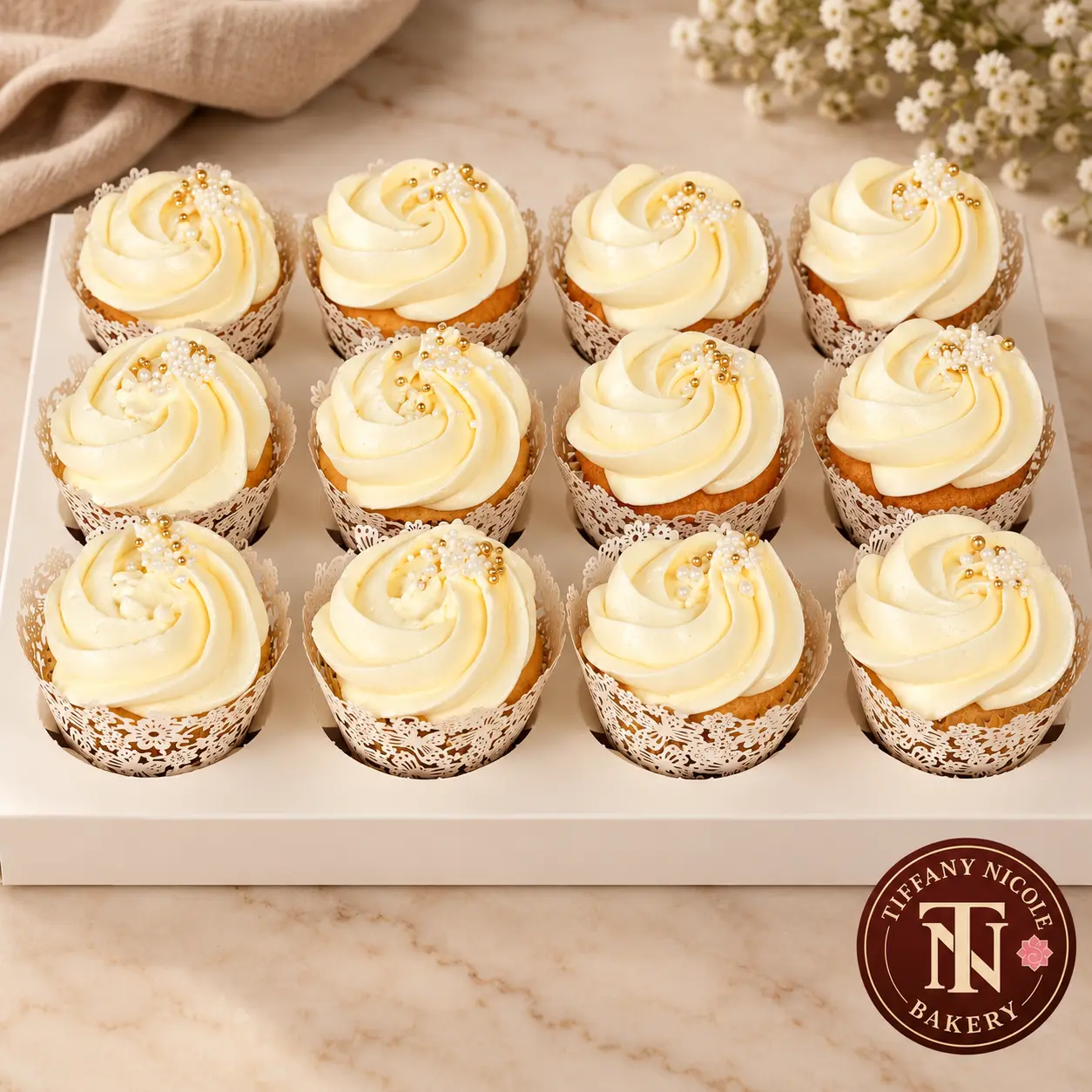 Ivory buttercream cupcakes in lace wrappers with gold and pearl accents
